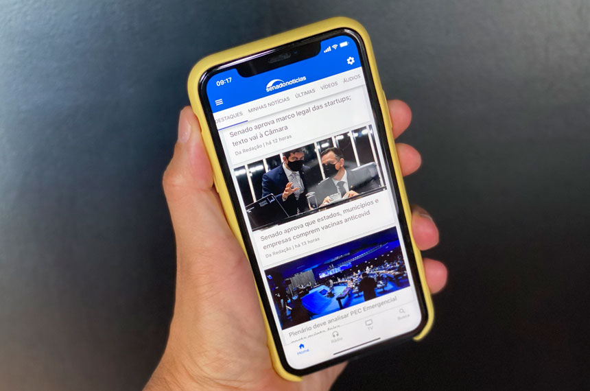 Pessoa usando smartphone no plenário do Senado.